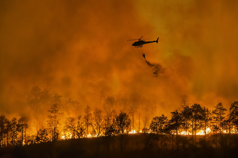 Fire fighting helicopter carry water bucket to extinguish the forest fire. Photo Contributor Toa55